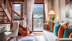 Une pièce comprenant un canapé, un bureau, une chaise, une table, une lampe et donnant sur la mer.