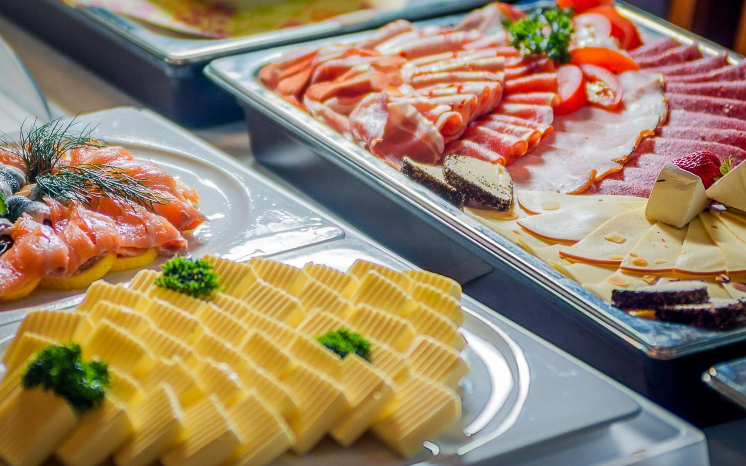 A buffet with various food items including smoked salmon, cheese, and other deli meats.