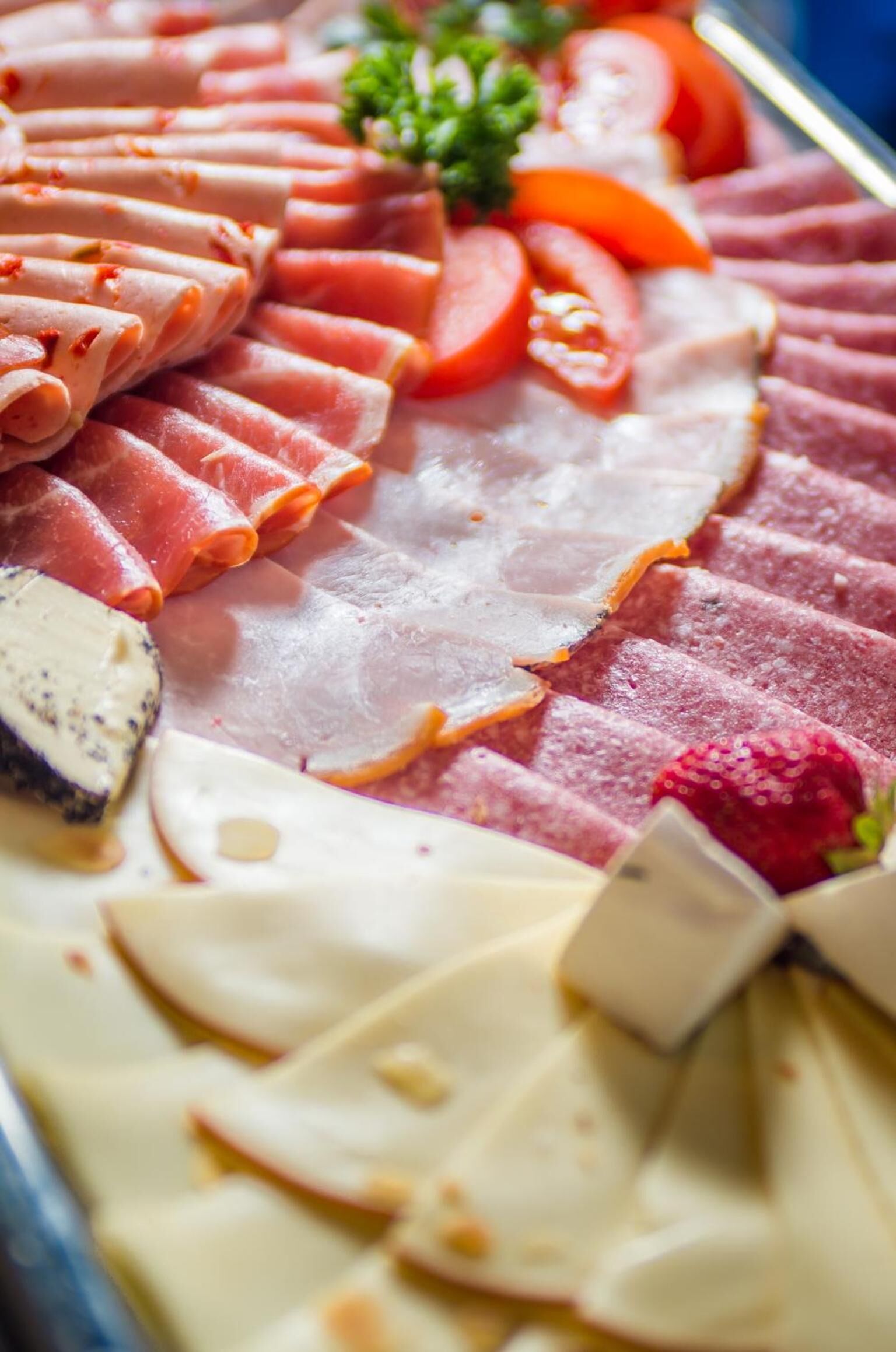 A charcuterie board with various meats, cheeses, and fruits.