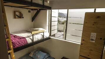 Habitación pequeña con literas, una mesita y ventana.