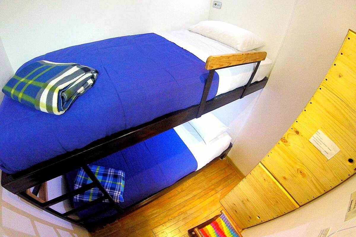 Un letto a castello con un materasso blu e una coperta a quadri sul letto inferiore.