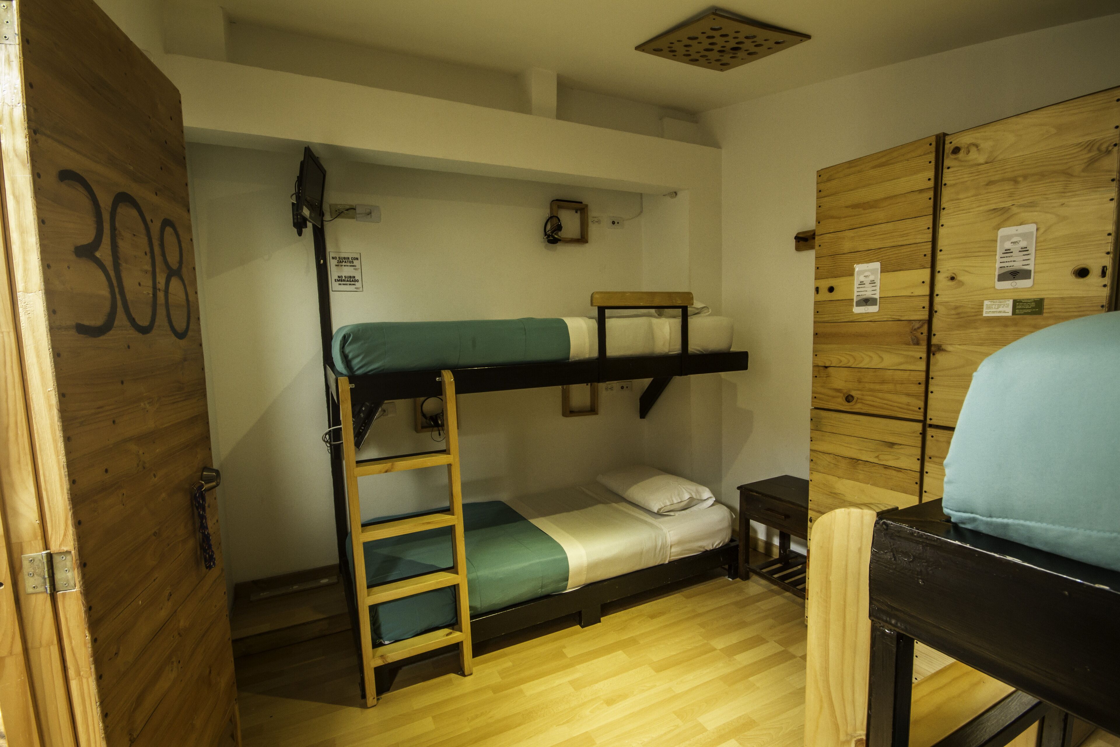 Une chambre avec des lits superposés, dont la porte en bois porte l’inscription « 308 ».