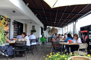 An outdoor café with tables and chairs, a covered area, and a view of the street. - Hostal De La 57 - Hostel (Manizales)