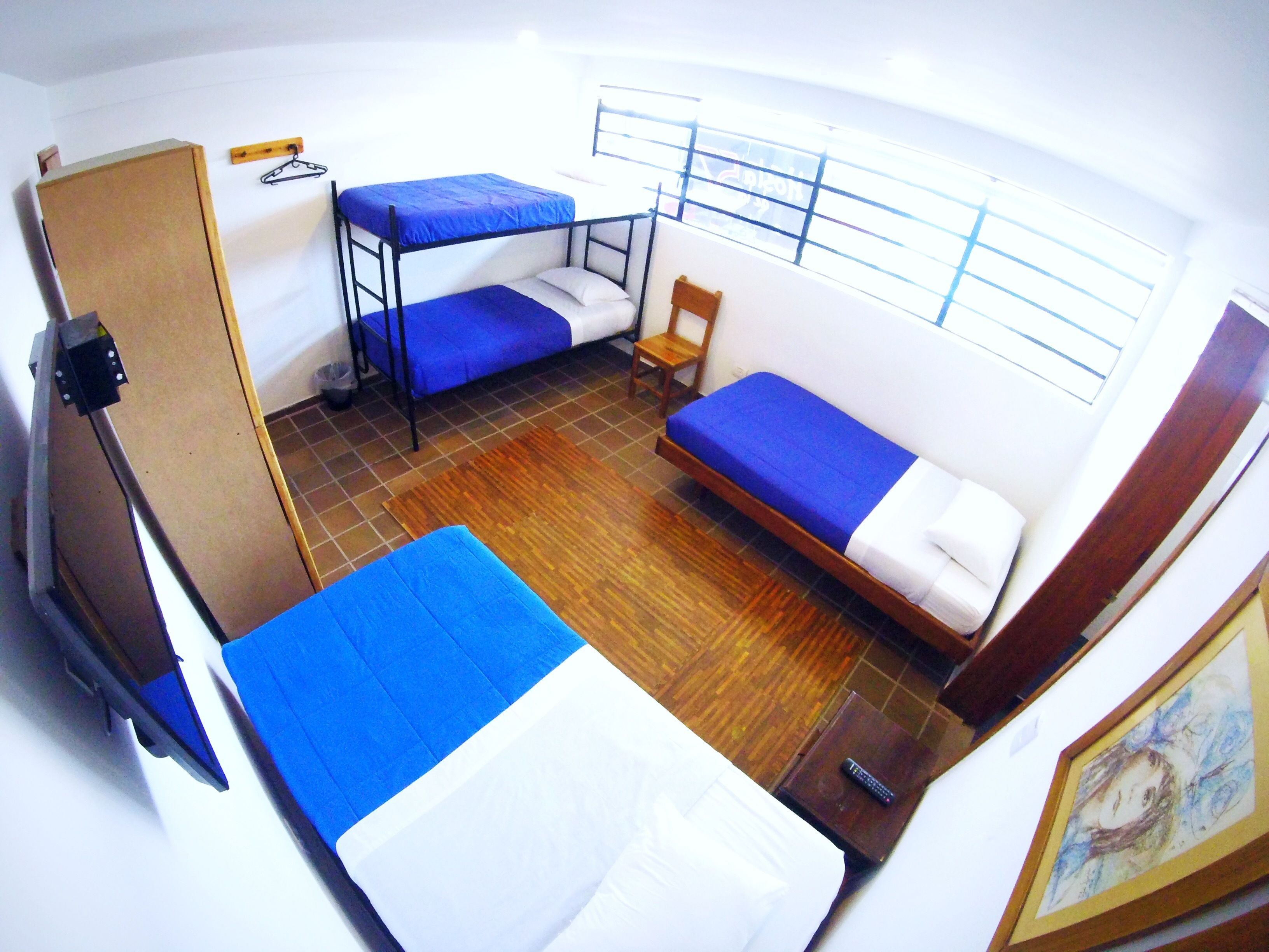 A compact room with two bunk beds, a wooden chair, a small table, and a window with bars.
