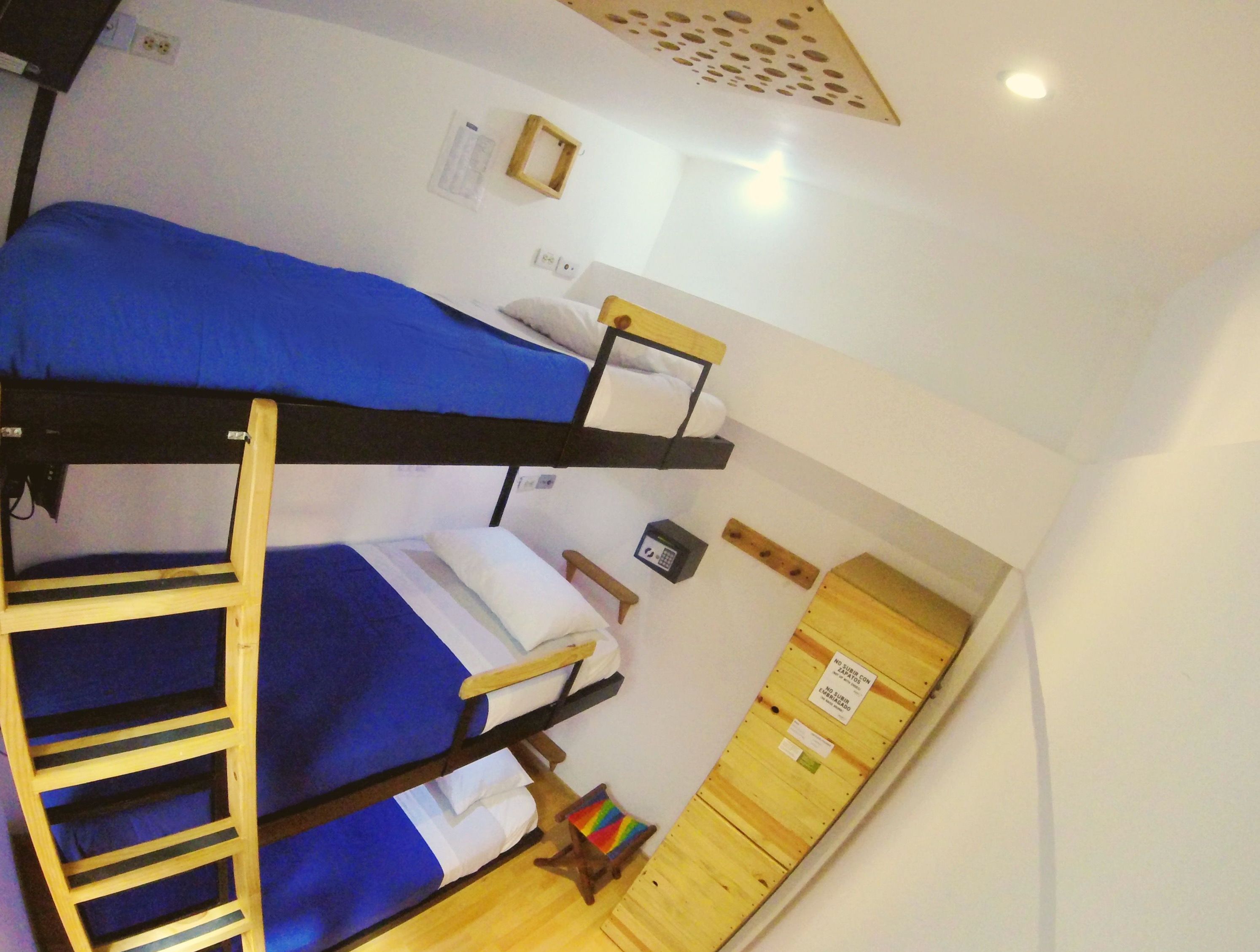 A dormitory room with bunk beds, a ladder, a small table, and a cabinet.