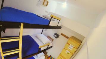 A dormitory room with bunk beds, a ladder, a small table, and a cabinet.