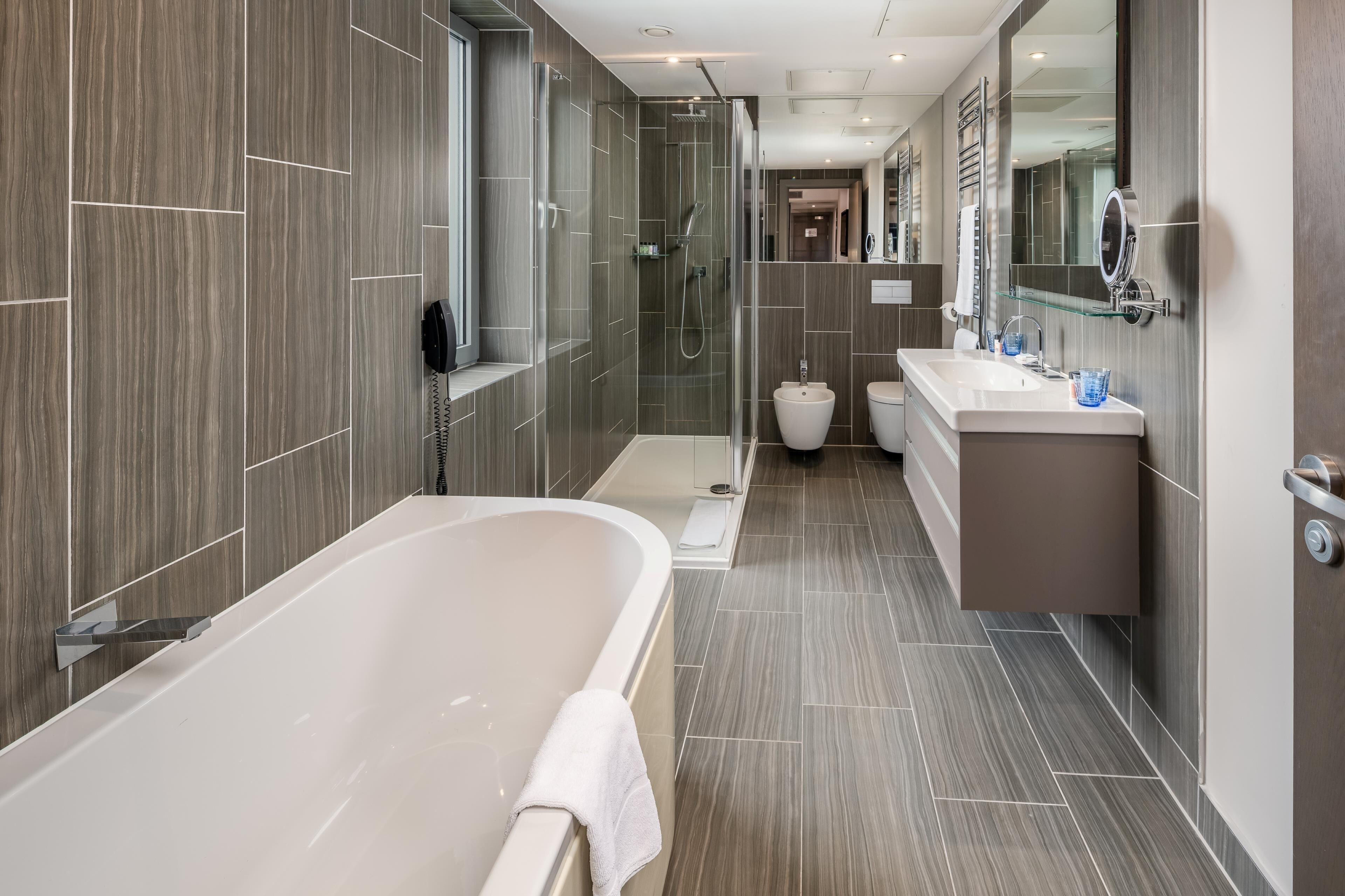Un bagno moderno con vasca, doccia e un mobile lavabo con specchio.