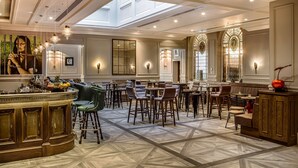 Un amplio vestíbulo de hotel con techo alto, una zona de bar central y un conjunto de asientos.