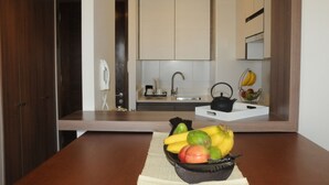 Une cuisine avec un saladier de fruits sur le comptoir, un évier et des placards.
