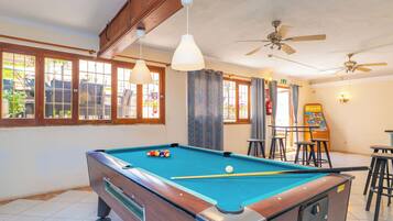 A pool table with balls, ceiling fans, and a bar area with stools.