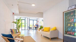 Een modern interieur met een zithoek, een automaat en een persoon achter een bureau.