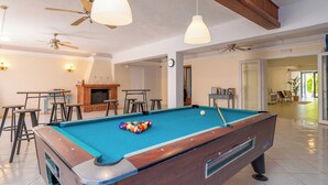 Een biljart, ballen, plafondventilatoren en een bar.