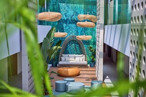 A modern interior with a wicker sofa, round ottomans, and hanging wicker lamps. - Universal Grand León & Spa (Ses Salines)