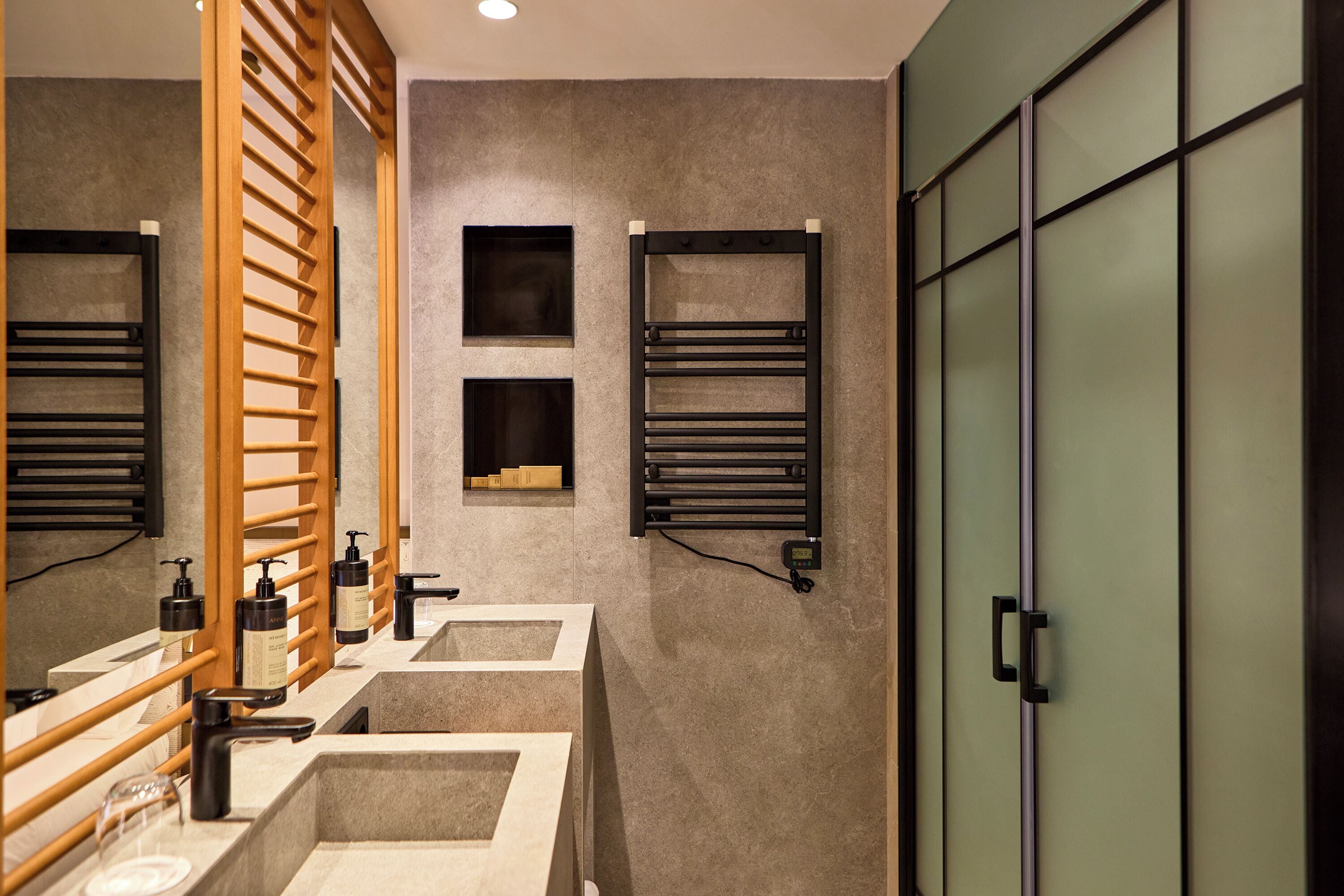 A modern bathroom with two sinks, wooden towel racks, and a large mirror.