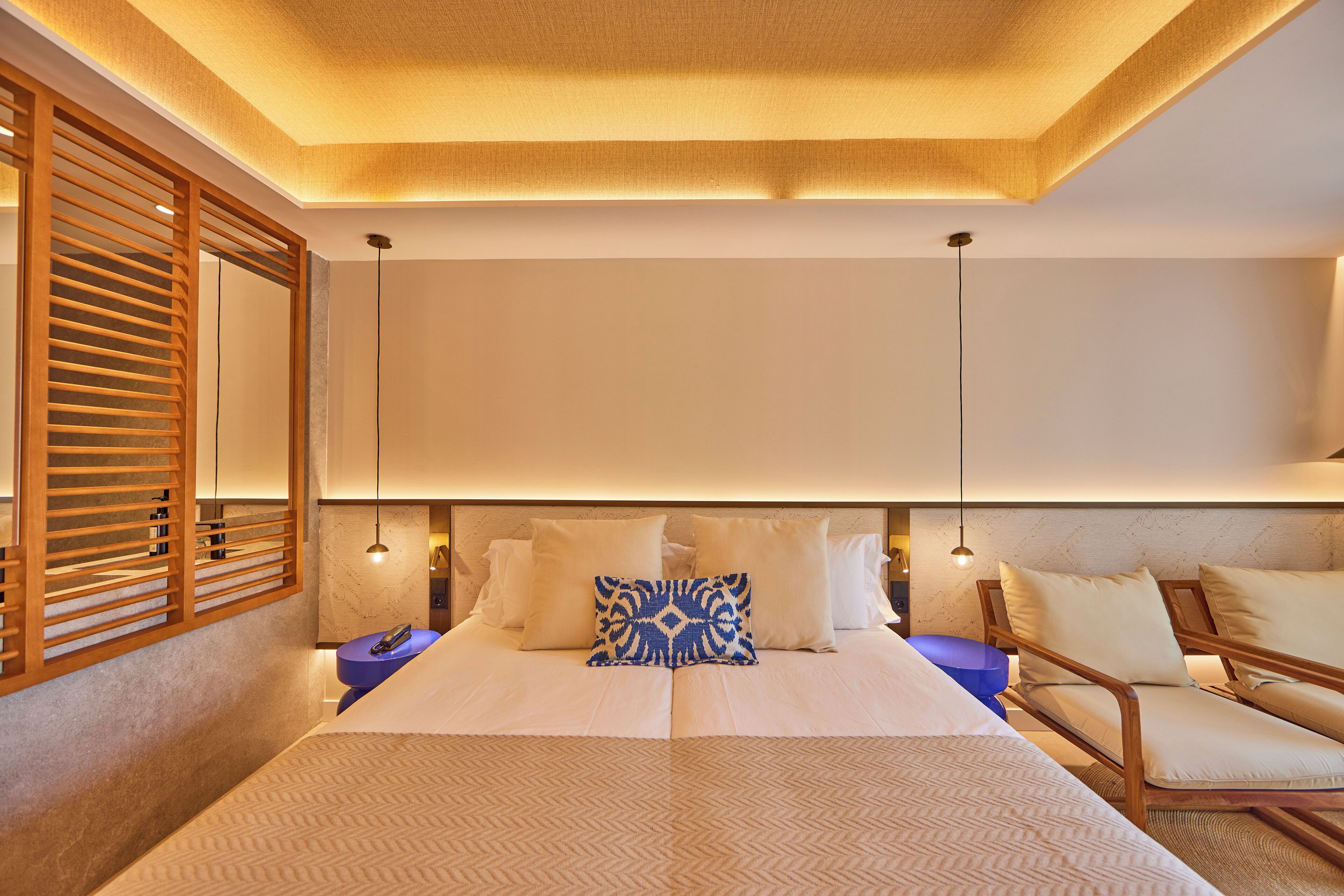 A modern hotel room with a large bed, wooden headboard, and a view of the city.
