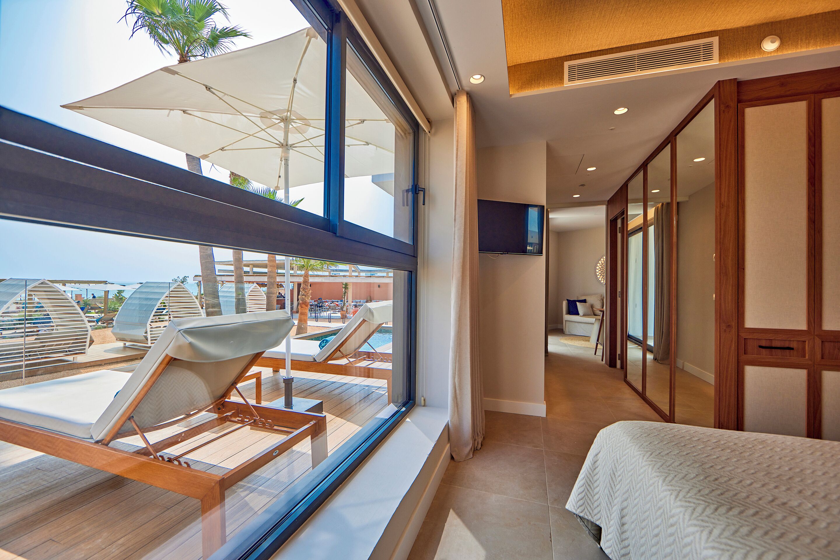 Une chambre d’hôtel avec une grande fenêtre, un lit, une télévision et une vue sur la piscine.