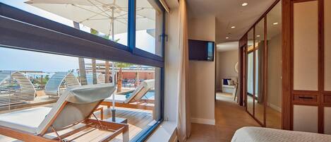Habitación de hotel con una ventana grande, una cama, un televisor y vista al área de la piscina.