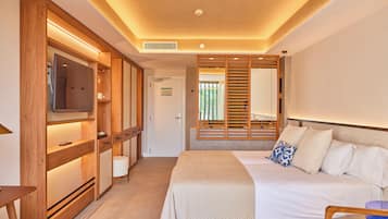 Una habitación de hotel moderna con una cama grande, un televisor, muebles de madera y un ventanal corredero que da a un balcón.