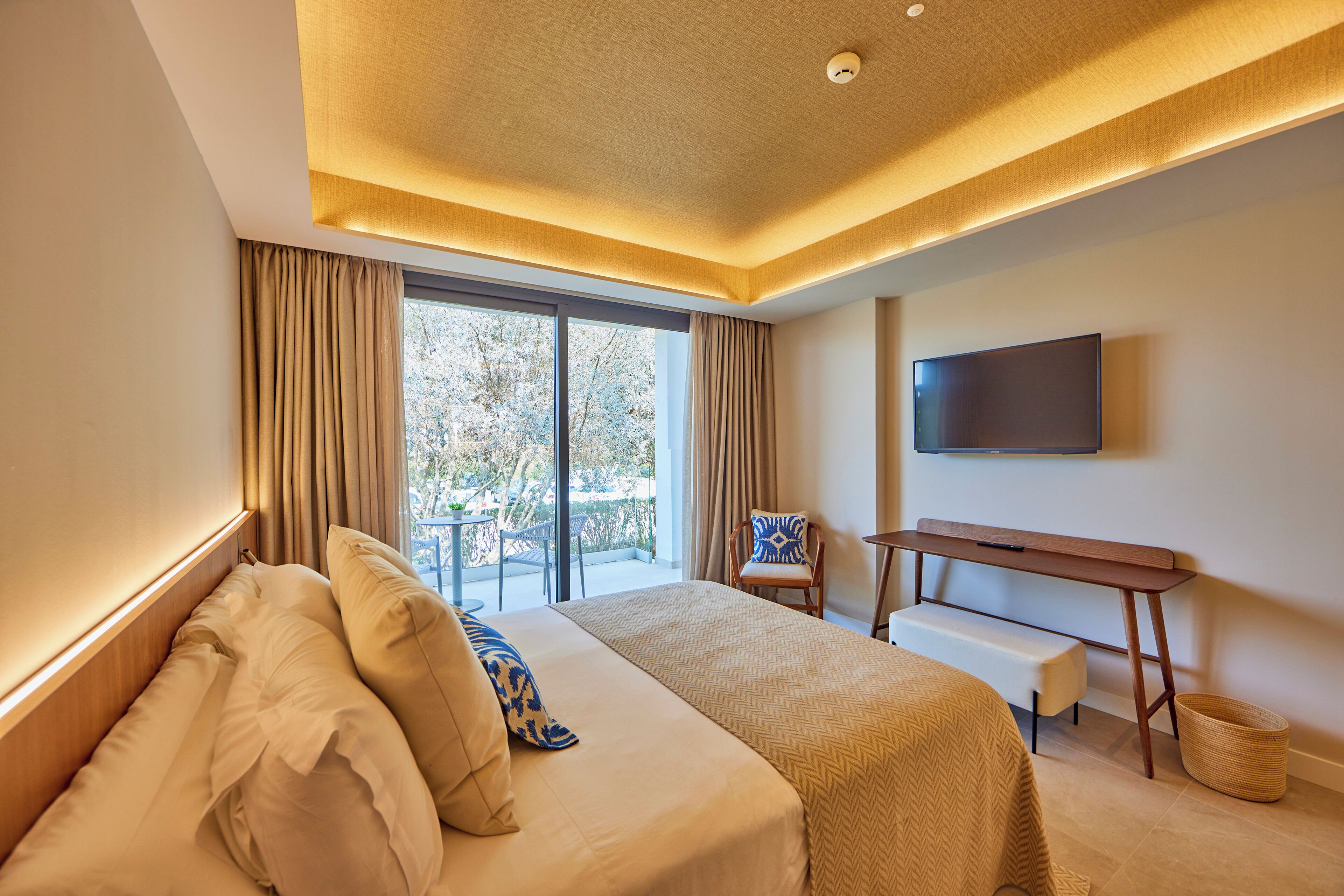 A modern hotel room with a large bed, a desk, and a television.