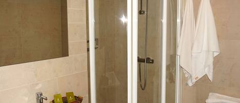 Un bagno con doccia vetrata, lavandino con articoli da toilette e WC.