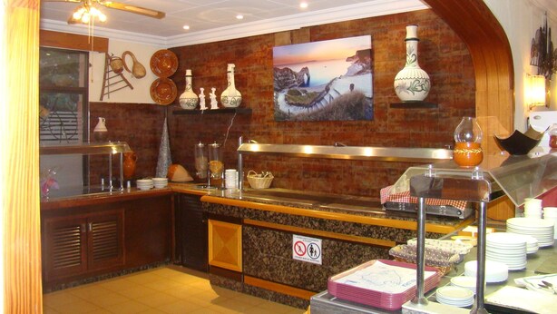 A buffet area with a brick wall, a ceiling fan, and a sign indicating no children allowed. - Residencia Santiago Mallorca (Santanyi)