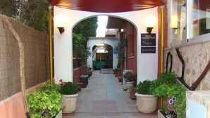 A hotel entrance with a red awning, potted plants, and a sign indicating the hotel name. - Residencia Santiago Mallorca (Santanyi)
