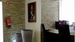 Habitació amb paret de pedra, un extintor, un paperer, un quadre amb marc i una taula amb cadires.
