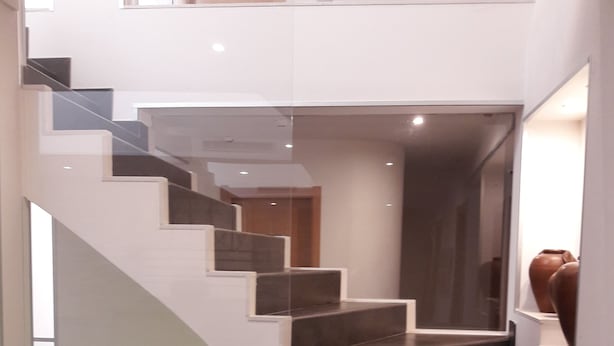 A modern staircase with glass railings and dark steps, leading to an upper level. - Guest House Bocage (Setubal)