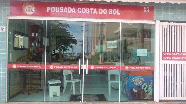 Fachada con un letrero que dice "POUSADA COSTA DO SOL" y un número de contacto.