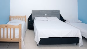 Un dormitorio con dos camas, una de madera y otra con estructura negra, frente a una pared azul y blanca.