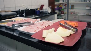 Una barra de buffet con diversos alimentos, como jamón en rodajas, queso y verduras.