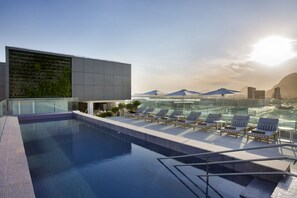 Una piscina al aire libre, sombrillas, tumbonas