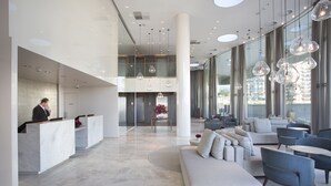 Um hall moderno com balcão de atendimento, área de estar e amplas janelas.