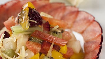 A bowl of fruit salad with a decorative red rim.