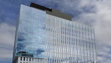 A modern high-rise building with a glass facade reflecting the sky.