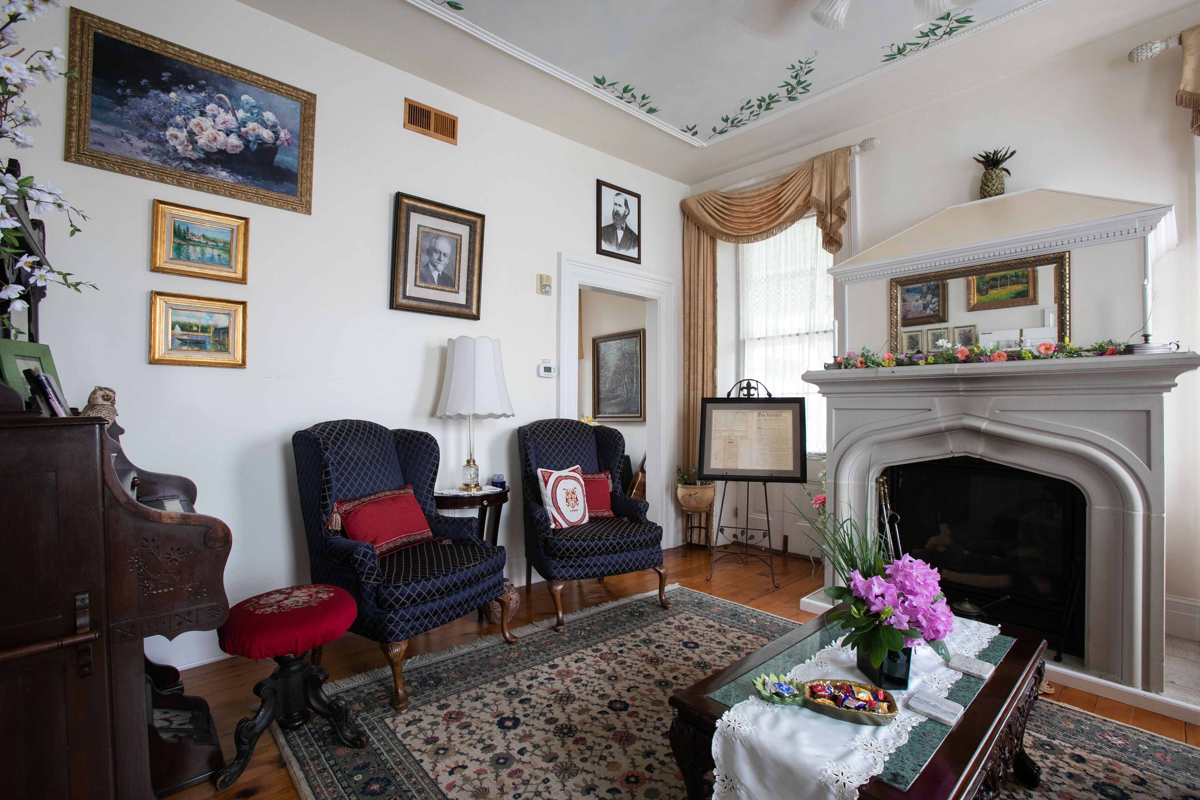 A traditional living room with a fireplace, framed artwork, and classic furniture.