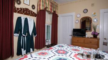 A bedroom with a bed, a dresser, a television, and a window with curtains.