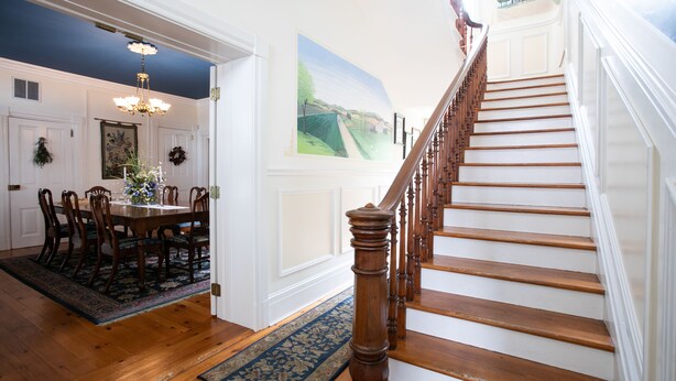 A staircase with wooden steps and a wooden handrail, leading to a landing with a white door. - E J Bowman House Bed & Breakfast (Lancaster)