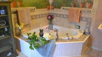 A bathroom with a freestanding bathtub, a vanity with a mirror, and a shelf with toiletries.