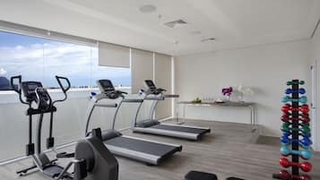 Un gimnasio moderno con cintas de correr, elípticas y un soporte para mancuernas.
