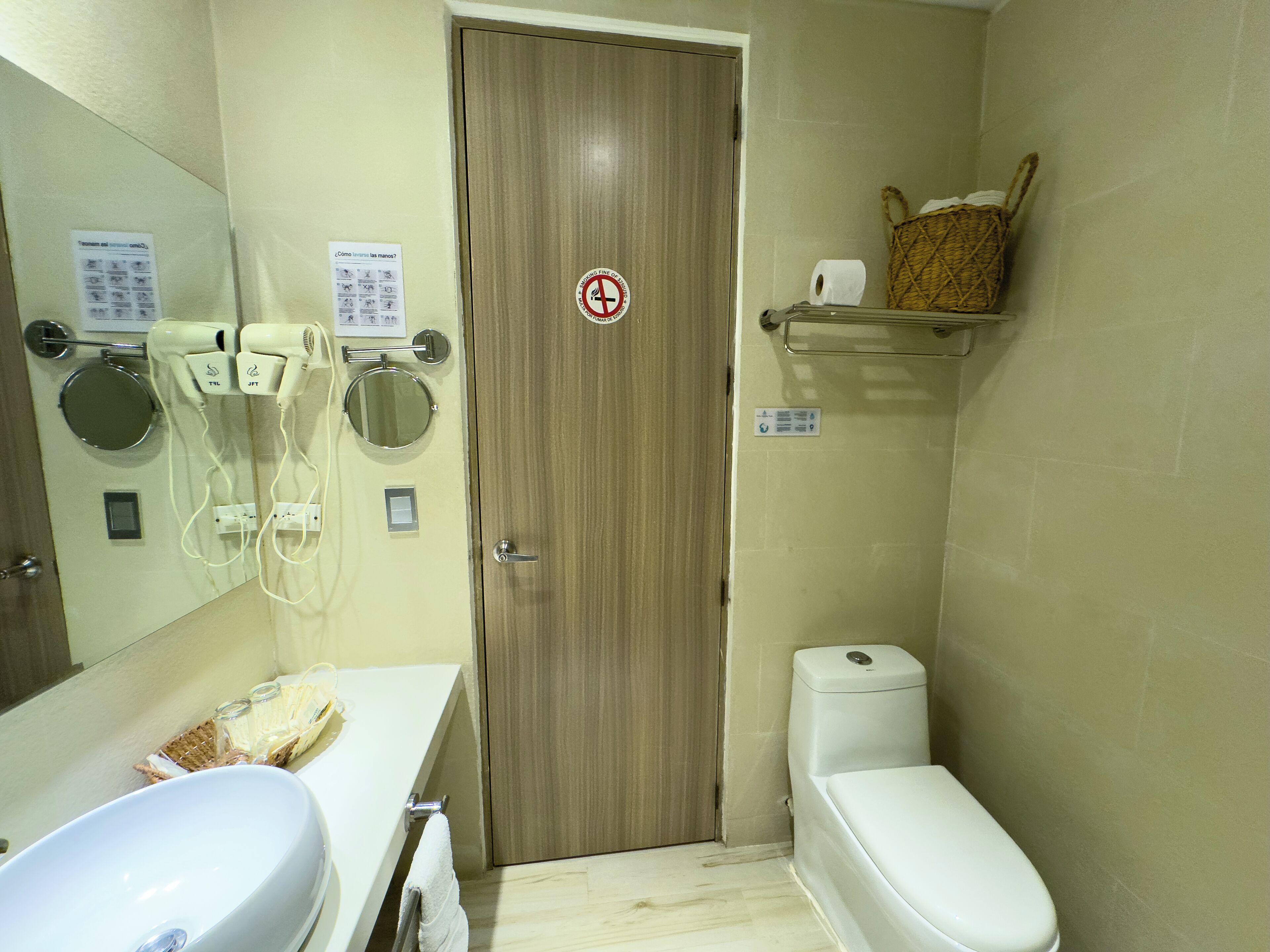 Une salle de bain équipée de toilettes, d’un lavabo, d’un miroir et d’un sèche-cheveux.