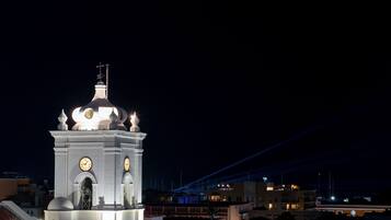 Una torre del reloj blanca con cúpula y cruz en la parte superior, rodeada de edificios.