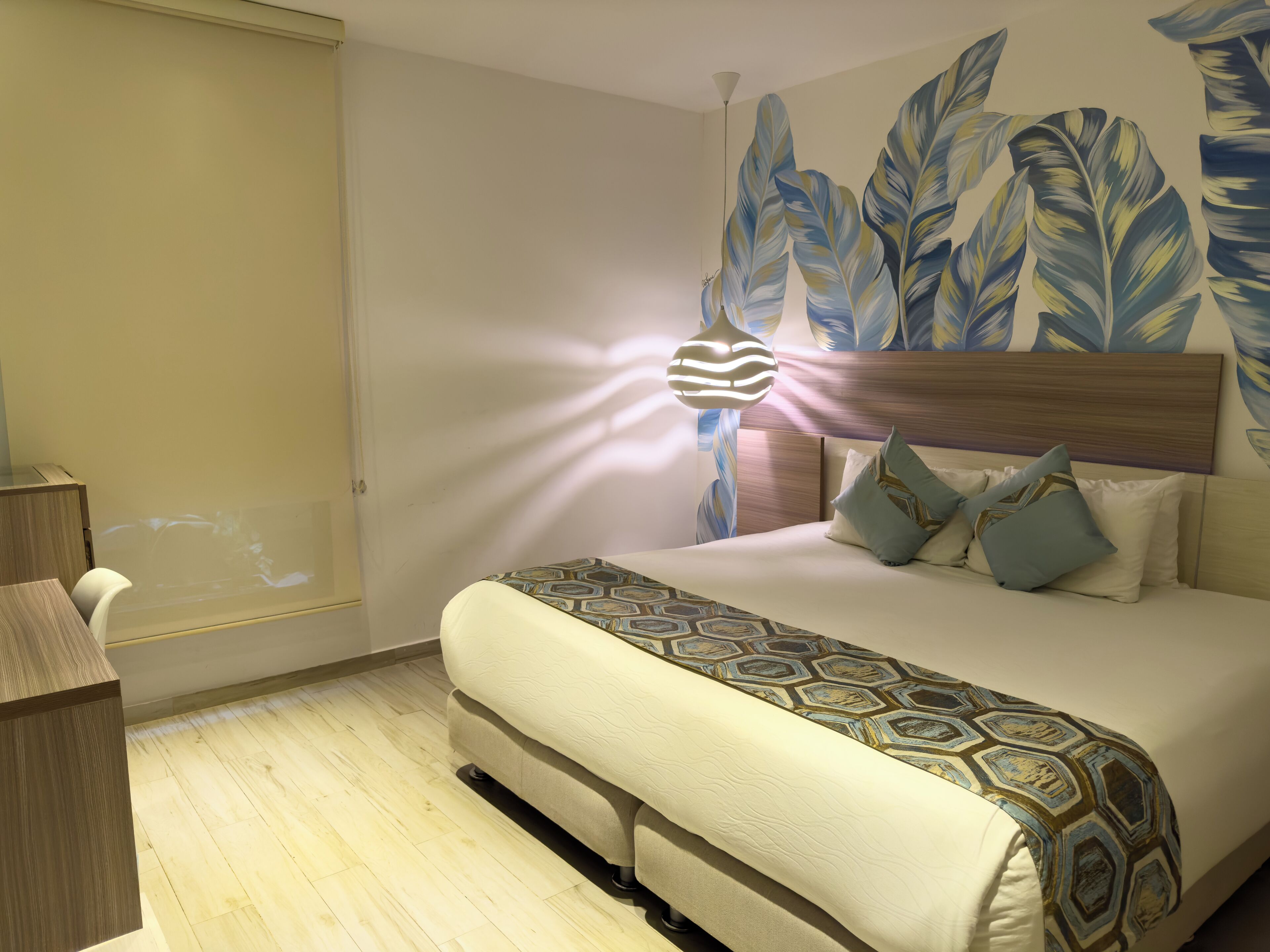 Une chambre d’hôtel avec un grand lit, une tête de lit en bois et un mur orné d’un motif de feuilles.