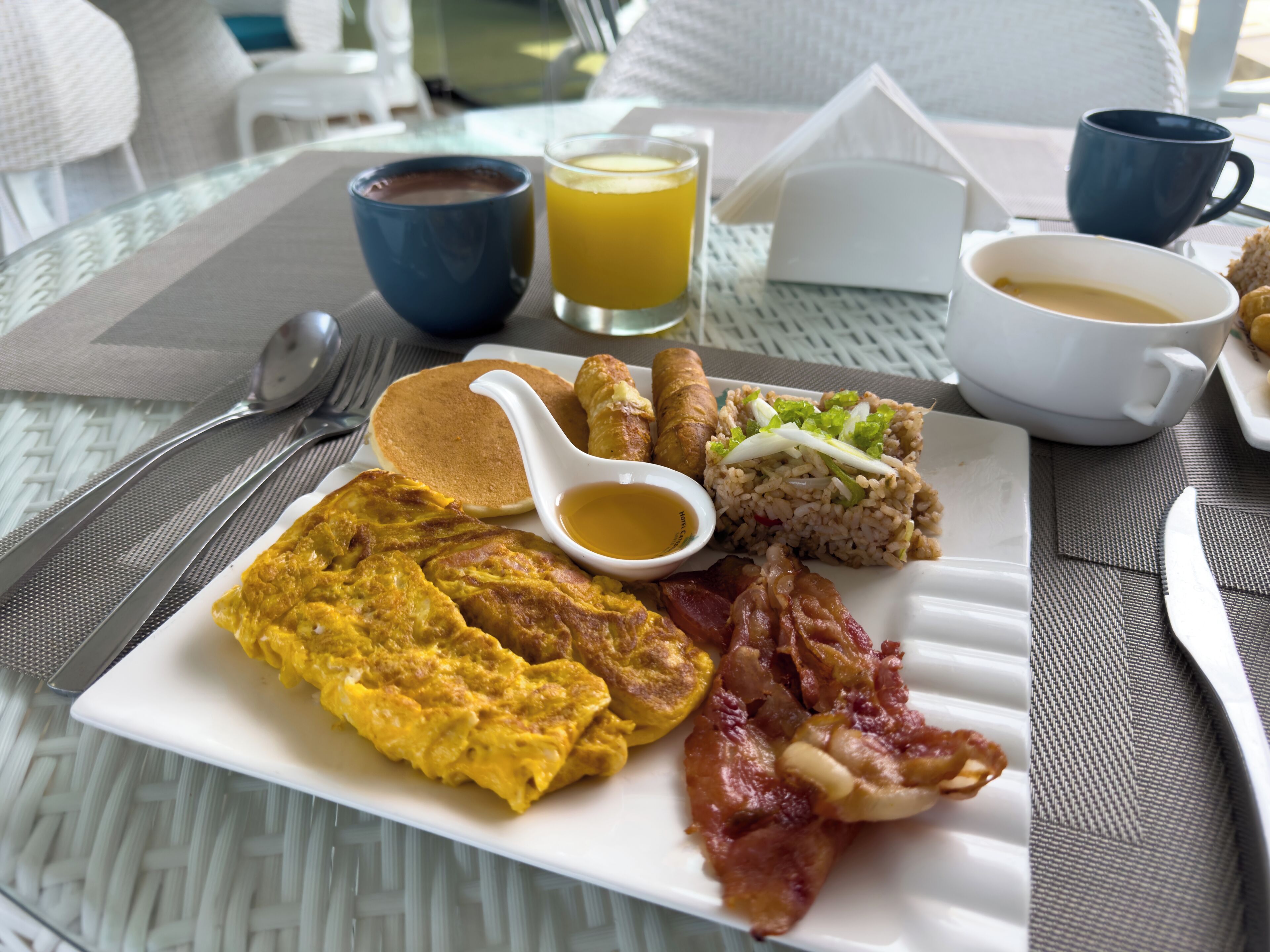 Un plato de desayuno con huevos, tocino y arroz.