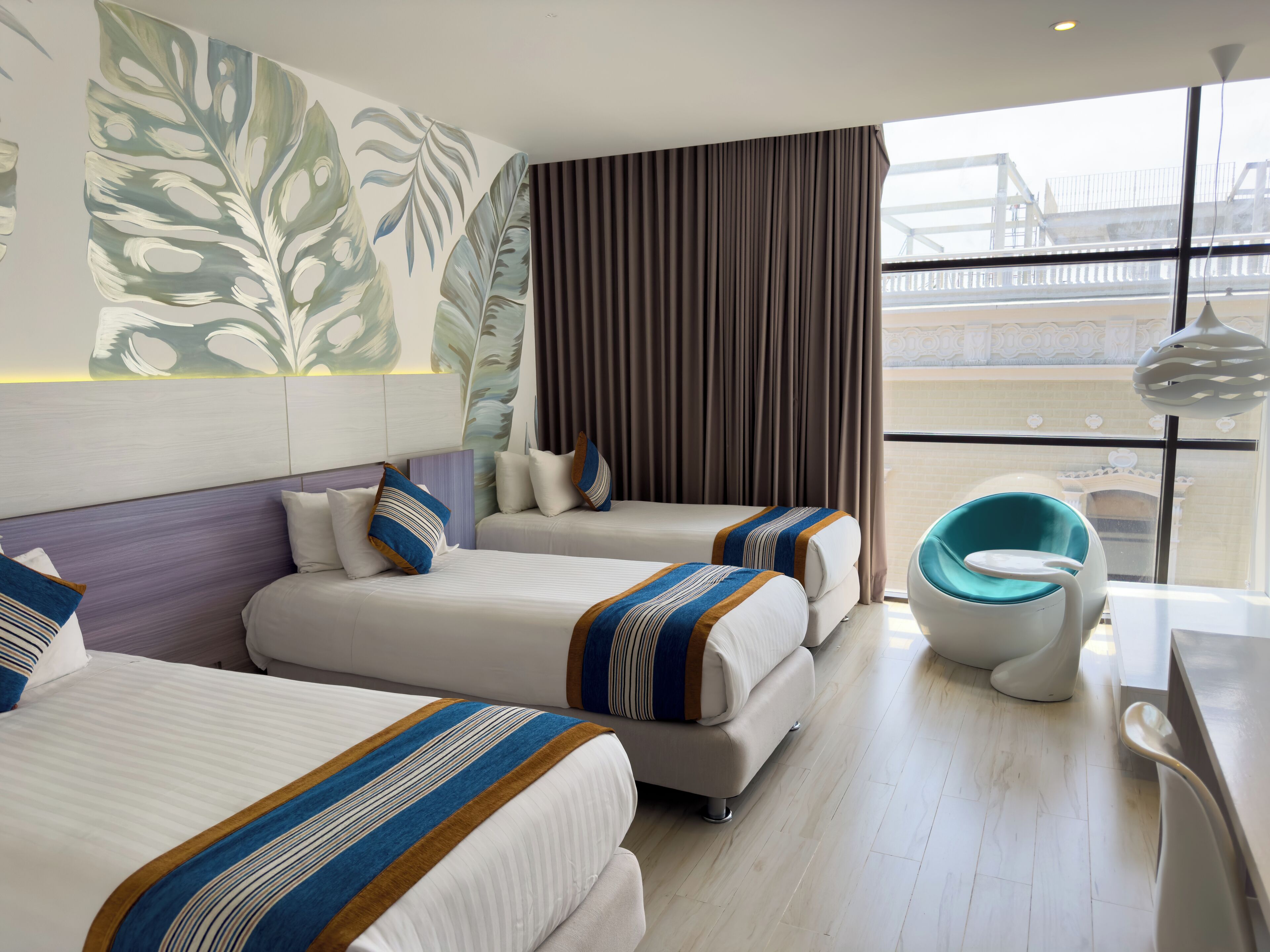 A hotel room with two beds, a large window with a view of a bridge, and a modern chair.