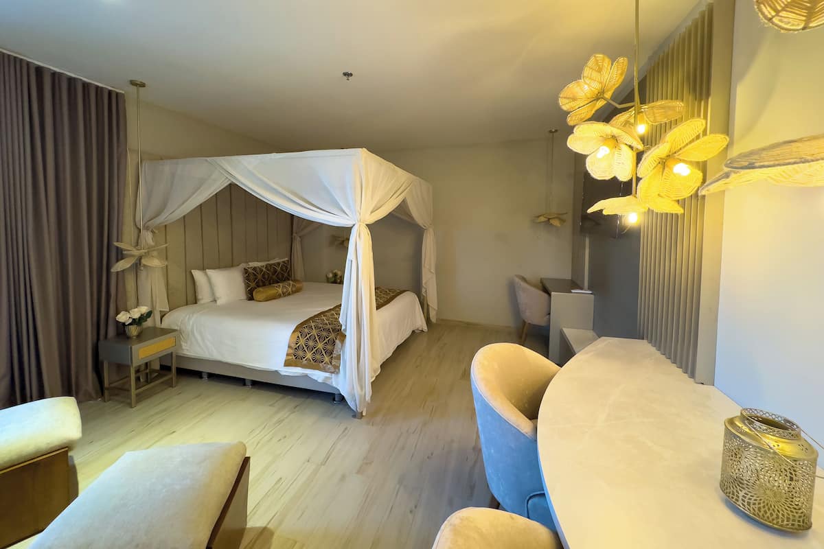 Een moderne hotelkamer met een hemelbed, een bureau, een stoel en een decoratieve wandlamp.