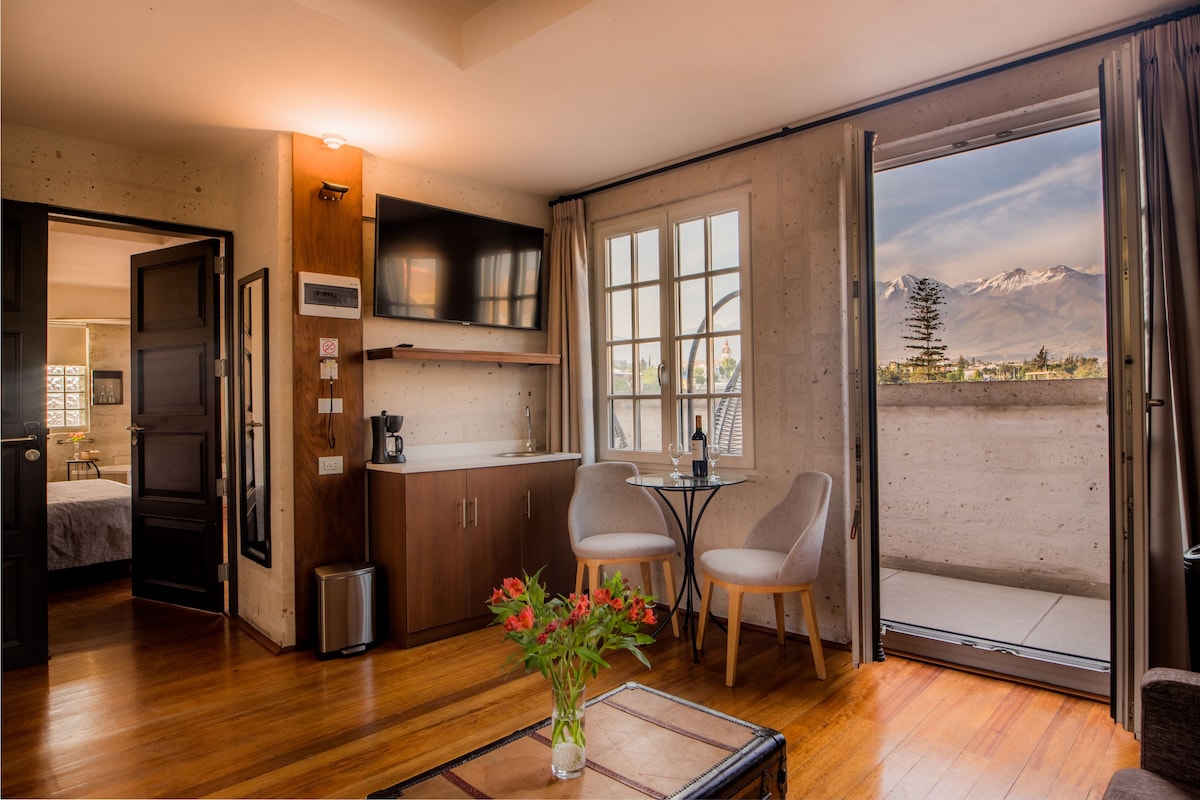 A modern kitchen with wooden cabinets, a built-in microwave, and a dining area with two chairs and a table.