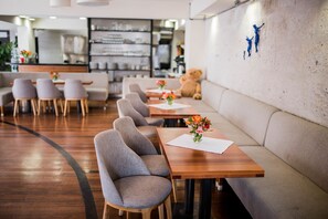 A modern restaurant with wooden tables and grey upholstered chairs.