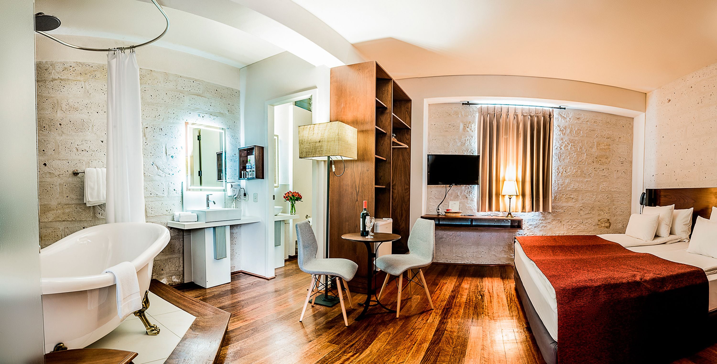 Een hotelkamer met een badkuip, een bureau met stoel, een bed en een televisie.