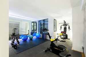 Un gimnasio con equipo de ejercicios, incluyendo una bicicleta estática, pelotas de ejercicios y mancuernas.